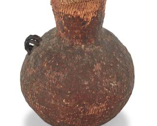 1176 An Apache pitch-covered basketry vessel Late 19th/early 20th century; Southwest United States A large coiled basketry water jar coated in pine pitch, with two multi-strand braided horsehair handles Height 11 in., width 9 in., depth 9 1/2 in. irregular Estimate: $200 - $400