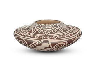 1040 Helen Naha (Feather Woman) (1922-1993, Hopi-Tewa) A black-on-white pottery low jar, circa 1970 With wide shoulder, decorated with black repeating zigzag, crosshatched, and swirling motifs below a meander-adorned shoulder, on white slip ground Signed in slip to underside with artist's feather device Height 5 1/4 in., diameter 13 in. Estimate: $1,200 - $1,800