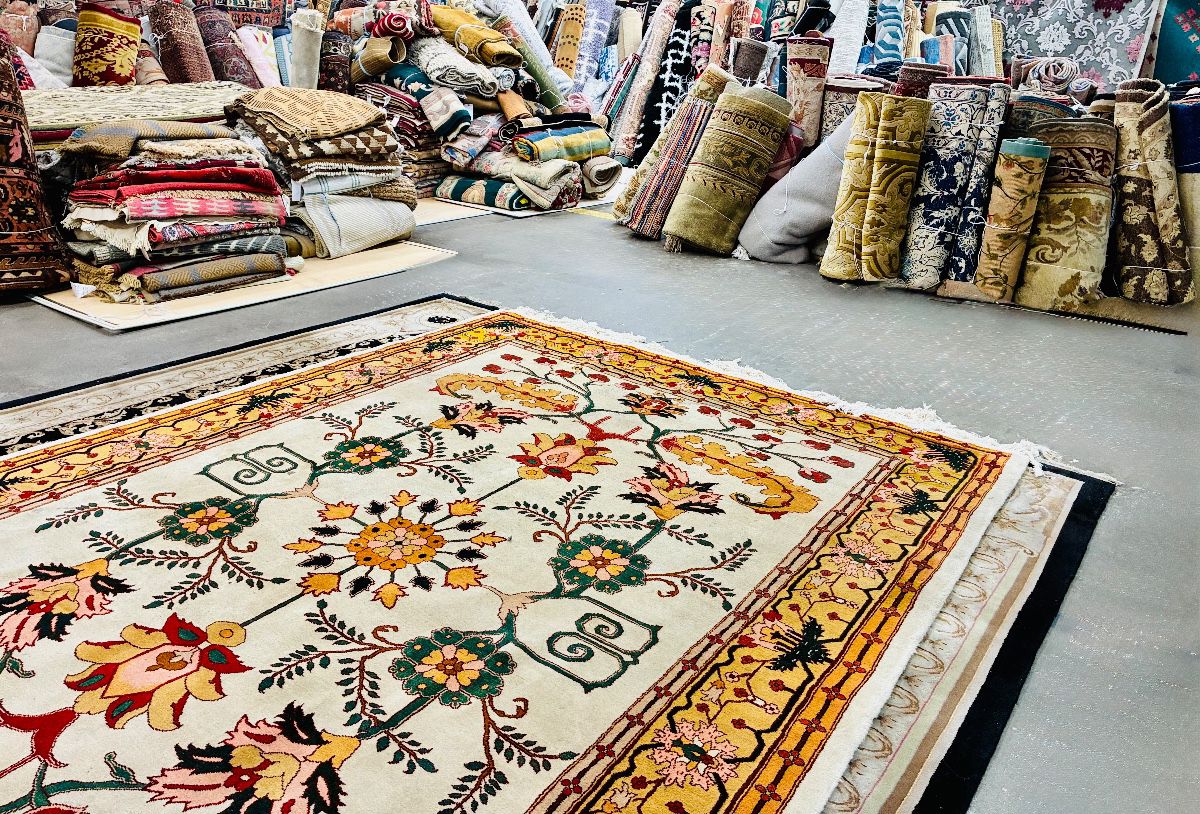 Showroom view featuring a colorful floral area rug surrounded by a large selection of rugs.