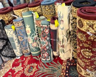 Assorted rolled traditional rugs featuring rich colors, patterns, and decorative designs.