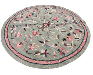 Round light blue rug with delicate floral patterning and a decorative border.