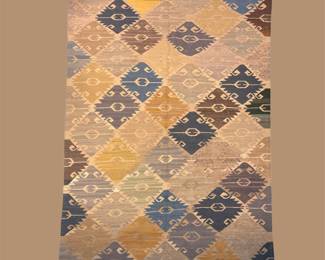 Colorful geometric patchwork rug with blue, gold, rust, and neutral tones.