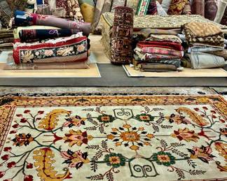 Showroom display featuring a colorful floral area rug with stacks of rugs available in the background.