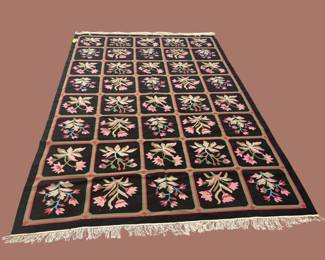 Dark traditional rug with repeating floral panels and rich decorative detailing.