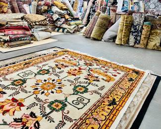 Showroom view featuring a colorful floral area rug surrounded by a large selection of rugs.