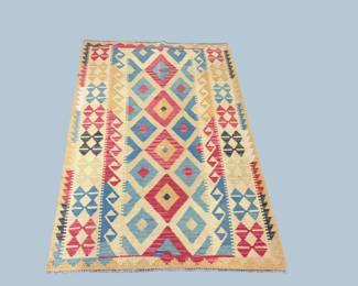 Colorful geometric rug with diamond motifs in red, blue, yellow, and ivory.