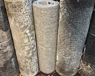Assorted neutral rolled rugs with classic traditional patterns and detailed borders.