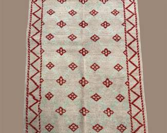Minimal ivory rug with a repeating red geometric pattern.