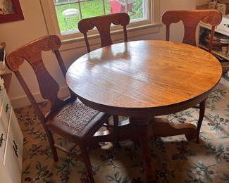 round oak table, 3 of the 4 cane seat chairs.