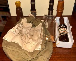 The bag in the foreground is a military personal effects bag for a fallen soldier and given to their family. This one was never used. On the right is a Faulk's H-100 Honker World Goose call.  Also shown are Herters Vit Glodo duck call and  a couple of Elam Fisher  trumpet end Tongue pincher duck calls. 