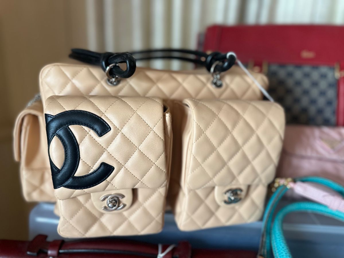 Chanel Cambon Ligne multi-pocket reporter bag in beige quilted leather with black CC logo and knotted shoulder straps.