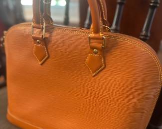 Louis Vuitton Alma handbag in Kenyan Brown Epi leather, featuring structured rolled leather handles and gold-tone hardware.