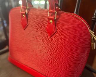 Louis Vuitton Alma handbag in red Epi leather, featuring gold-tone hardware and dual rolled top handles.