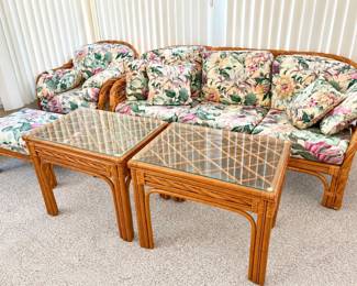 a vintage tropical rattan and bamboo living room furniture set with floral cushions and glass-top tables. 