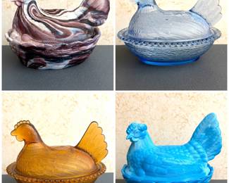 a collection of four vintage glass "hen on nest" covered candy dishes. Including colors such as slag glass, blue, and amber