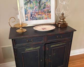 Distressed 2-drawer cabinet and shown with LeRoy Neiman print, brass hurricane lamp, and brass hurricane candle holder