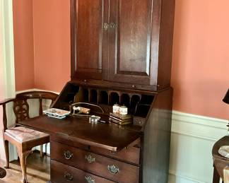 English oak secretary with full front desk, pigeonholes, and three drawers below. Upper cabinet with arched panel doors.