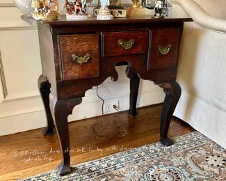 Queen Anne style oak lowboy with three drawers, shaped apron, and cabriole legs.
