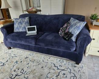 This sofa is slip covered in blue velvet. Underneath it is a beautiful brown fabric sofa