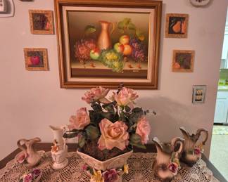 Vintage still-life framed art and plaques; hand-crocheted runner with floral detail; Vintage Mid-20th Century Capodimonte porcelain 2 pc vase set,  Vintage Nuova Capodimonte floral pitcher, Vintage mid-late Century Capodimonte footed flower planter centerpiece with added Rose arrangement; Vintage Mid-Century Wales Japan ceramic pitcher vase, and a Thorley bone china  rose figurine crafted in Staffordshire, England