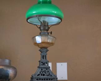 Vintage oil lamp with green glass shade and ornate metal base.