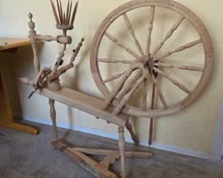 large traditional Saxony-style/flax spinning wheel with a distaff, single treadle, flyer/bobbin assembly, and a large turned-wood drive wheel.