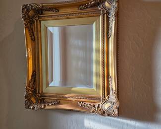 ornate, gold-toned wall mirror