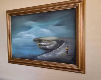 Framed moody coastal painting with figure, shoreline, and dramatic stormy sky.
