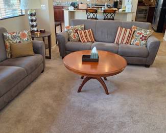 round wooden coffee table featuring a warm finish and flared, curved leg