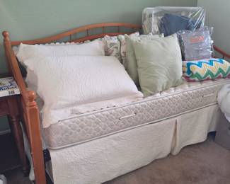 wood daybed with a slatted/spindle-style back and sides, shown with a twin mattress
