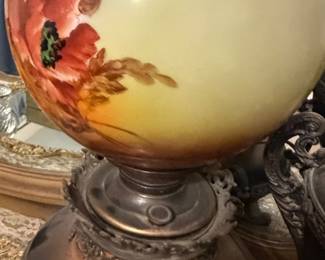 Antique Victorian-style "Gone with the Wind" parlor oil lamp featuring a large hand-painted glass globe with a floral poppy design and an ornate metal base