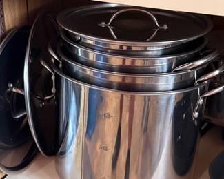 Set of stainless steel stockpots with integrated stamped measurement markings 4, 8, and 12-quart lines on the largest pot