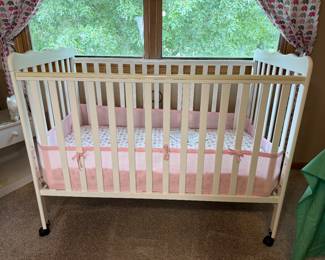 White wooden crib with caster wheels