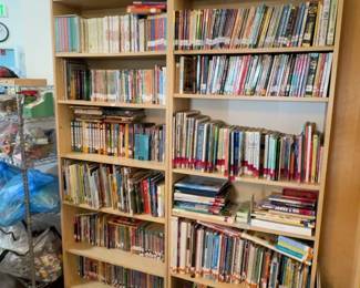 LE045 Two tall wood bookcases filled with childrens books cultural objects displayed on top