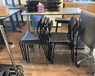 LE059 Stacked black perforated classroom chairs additional furniture behind