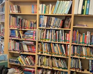 LE039 Multiple tall wood bookcases filled with categorized childrens books and cultural artifacts
