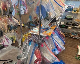LE028 Rolling wire rack densely hung with individually bagged lessons side view