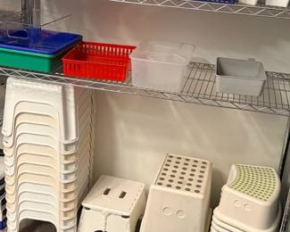 TS022 Plastic classroom traysbaskets on shelving with stacks of white step stools below