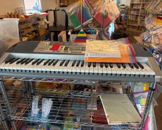LE069 Casio electronic keyboard on wire shelving with music lesson materials
