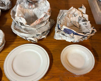 Lot 35: White ceramic dinnerware set with newspaper-wrapped pieces