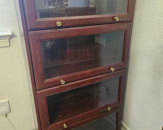 A four-tier wooden stacking barrister bookcase with glass doors.