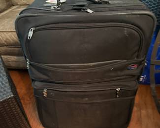 Black soft-sided rolling suitcase with multiple zip pockets