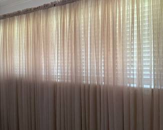 Sheer floor-length curtains in beige over wood plantation blinds
