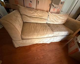 Beige velvet upholstered loveseat with skirted base