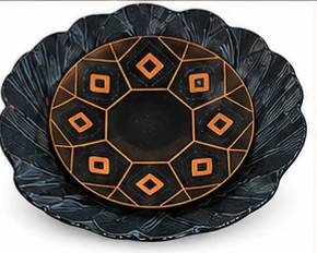 Large black decorative bowl with raised textured edges and copper-colored geometric accents.