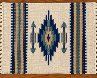 Southwestern woven rug with blue and tan geometric design and fringed edges.