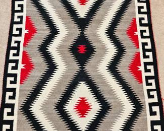 Southwestern woven rug with bold geometric diamond pattern in black, cream, gray and red, finished with a Greek-key style border.