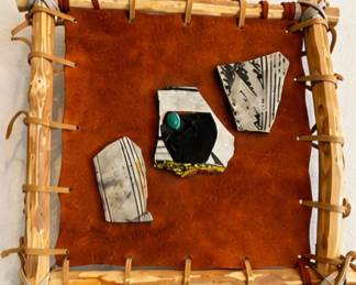 Southwestern-style wall art with rustic wood frame, leather backing and geometric stone inlays.