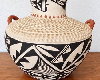 Southwestern pottery vessel with bold black geometric designs, textured detailing and terracotta handles.
