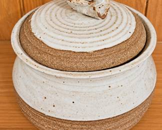 Handcrafted stoneware lidded jar with a speckled cream glaze, natural brown clay accents, concentric ring detailing and sculptural lid handle.